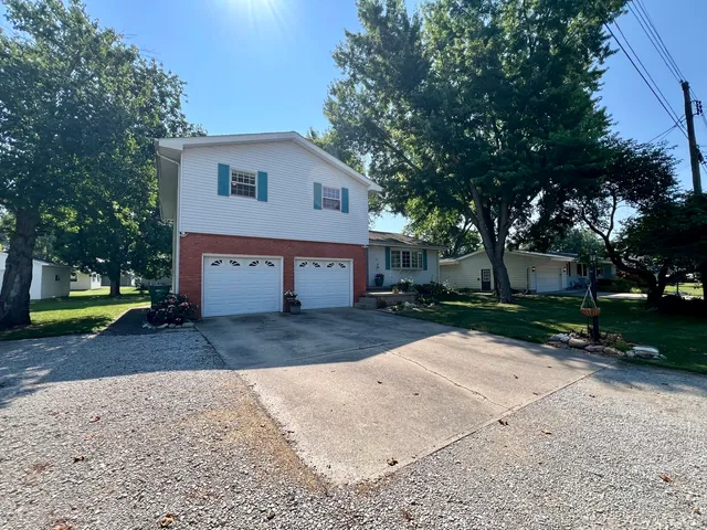 a view of a house with a yard and large tree