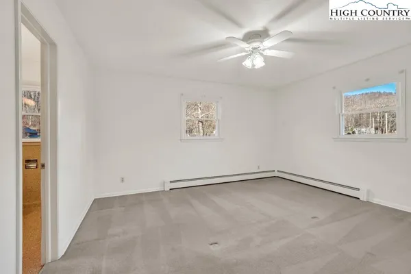 an empty room with windows and fan