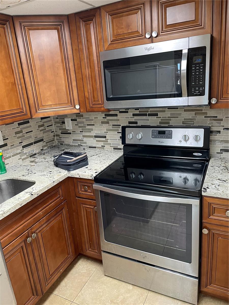 Ives Estates Miami, FL 33179 - Photo 30 of 34 a kitchen with stainless steel appliances granite countertop a stove microwave and cabinets