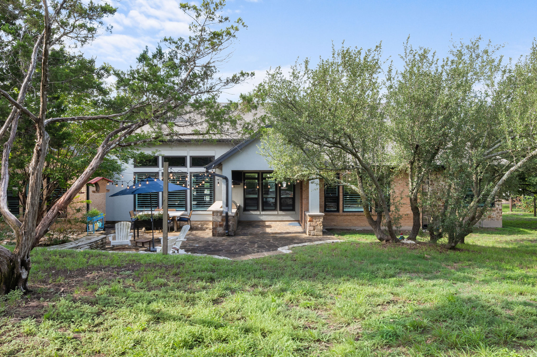 279 Rugged Earth Drive Austin, TX 78737 - Photo 37 of 39 A spacious backyard with mature trees frames a charming patio, perfect for outdoor gatherings.
