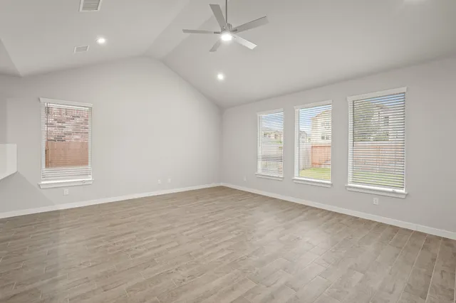 a view of an empty room with a window and wooden floor