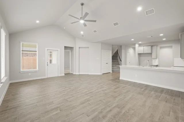an empty room with wooden floor and kitchen view