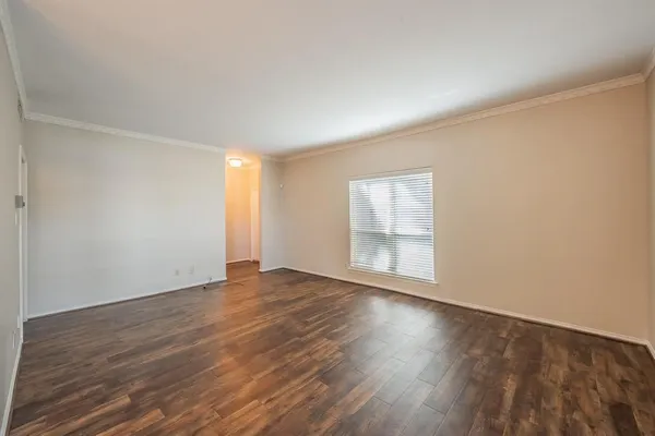 a view of an empty room with wooden floor and window