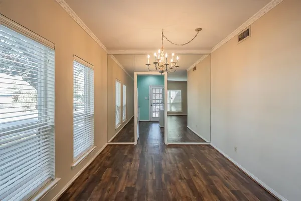 a view of a hallway with wooden floor and chandelier