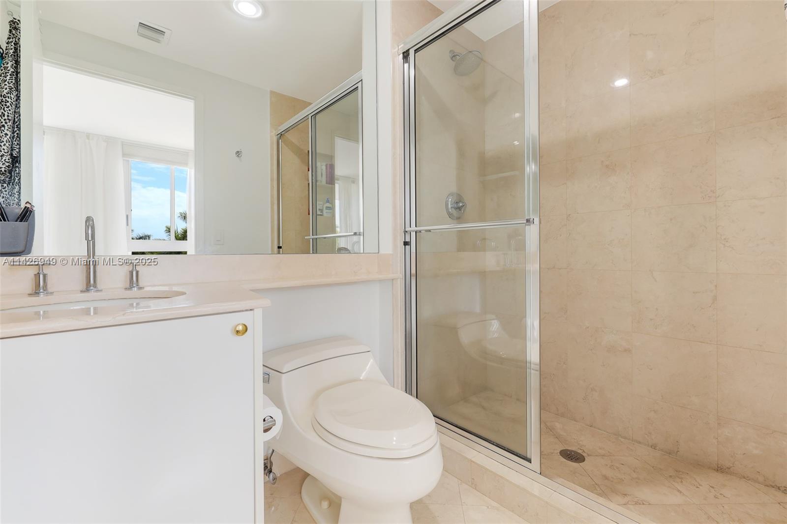 789 Crandon Boulevard, Unit 403 Key Biscayne, FL 33149 - Photo 13 of 27 a bathroom with a shower sink vanity mirror and toilet
