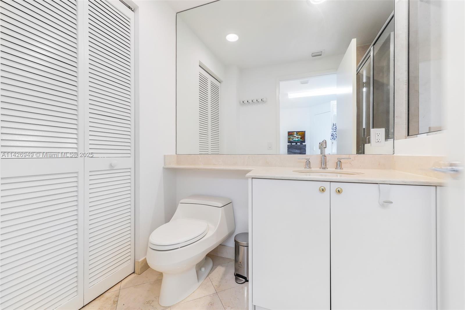 789 Crandon Boulevard, Unit 403 Key Biscayne, FL 33149 - Photo 20 of 27 a bathroom with a toilet a sink and mirror