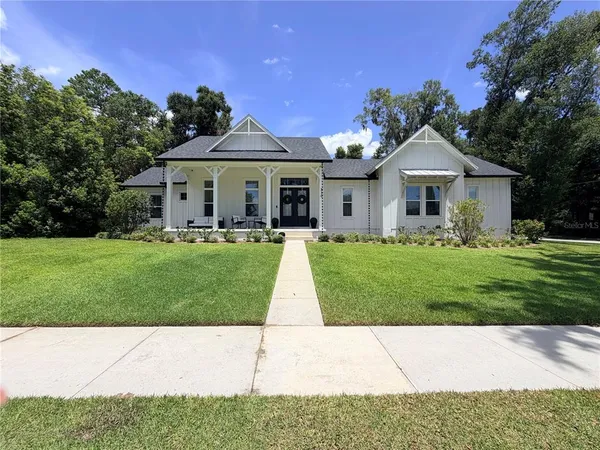 a front view of a house with a garden and trees