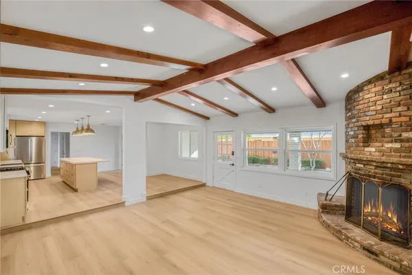 a view of an empty room with wooden floor and a fireplace