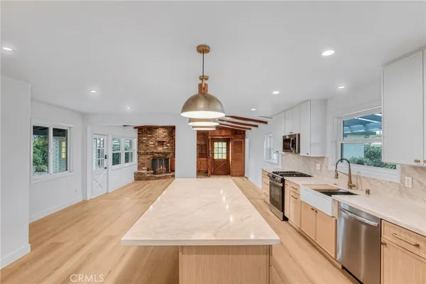 a large kitchen with stainless steel appliances granite countertop a large counter top a stove and a sink