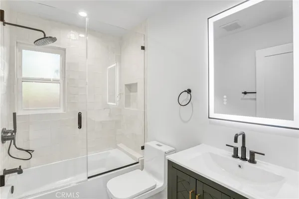 a bathroom with a shower sink vanity mirror and toilet