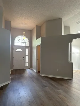 an empty room with wooden floor cabinet and windows