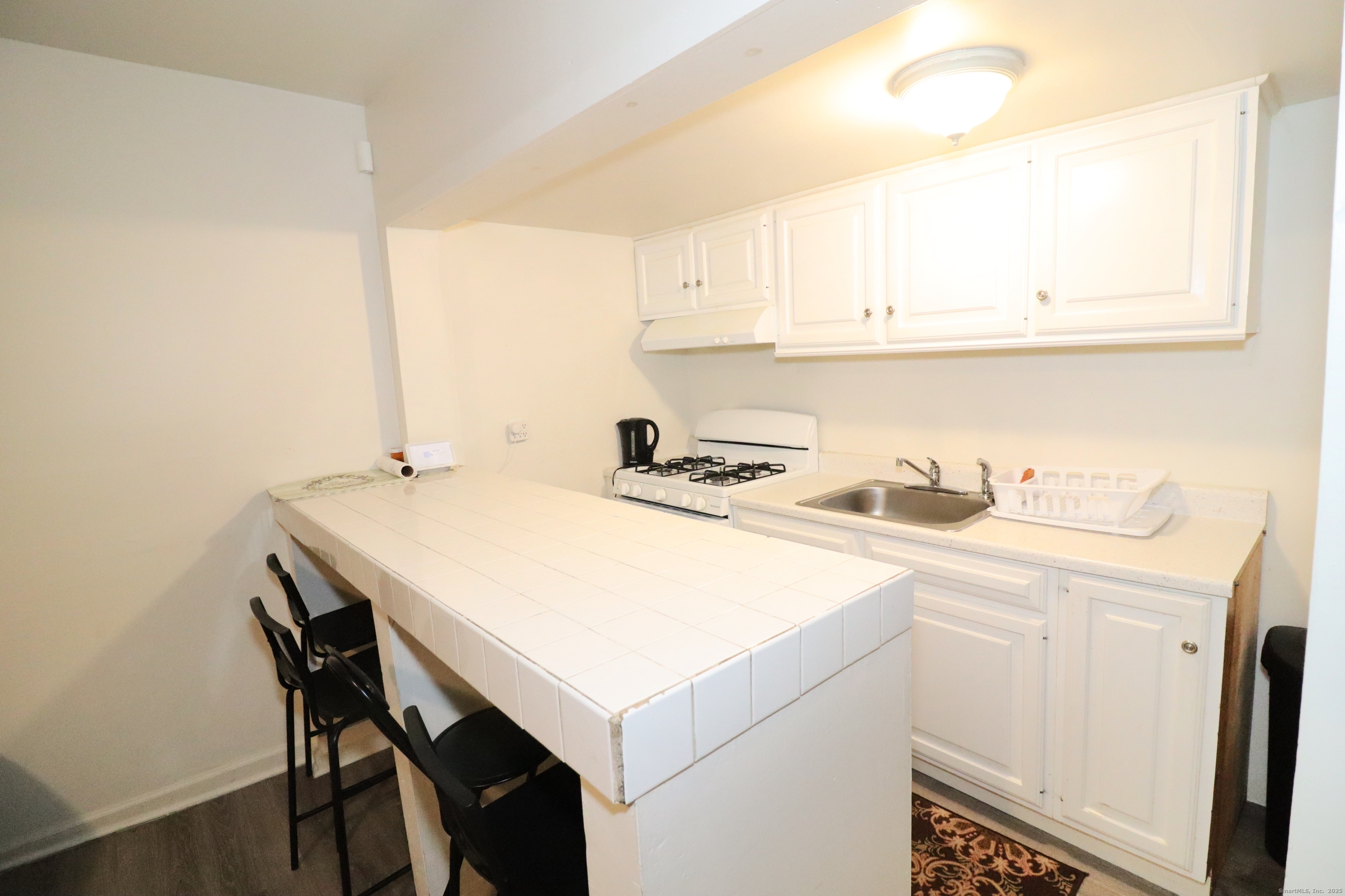60 Olive Street Bridgeport, CT 06605 - Photo 13 of 34 a kitchen with a sink a stove and white cabinets