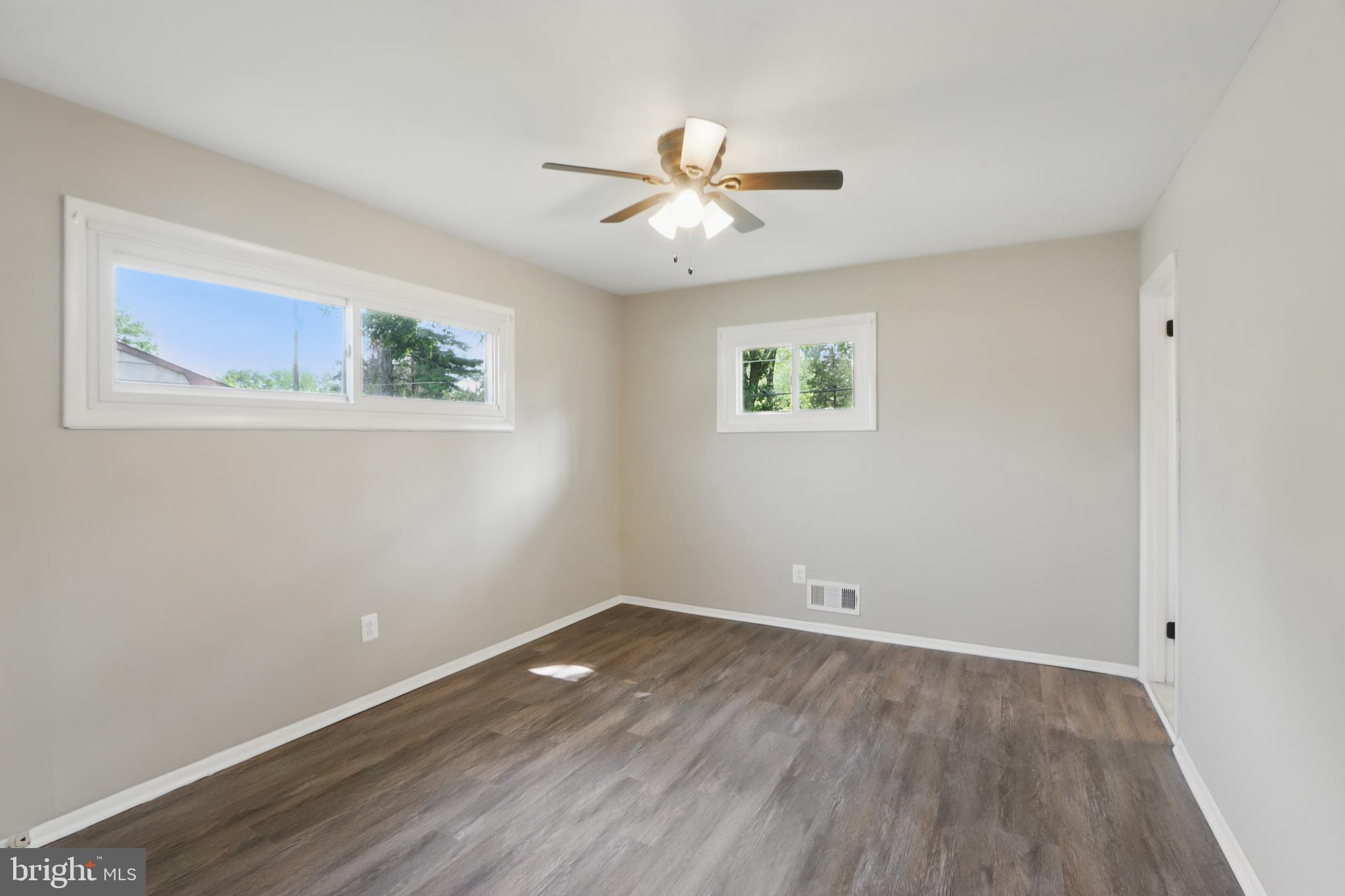 9021 Meadow Heights Road Randallstown, MD 21133 - Photo 24 of 41 a view of an empty room with wooden floor and a ceiling fan