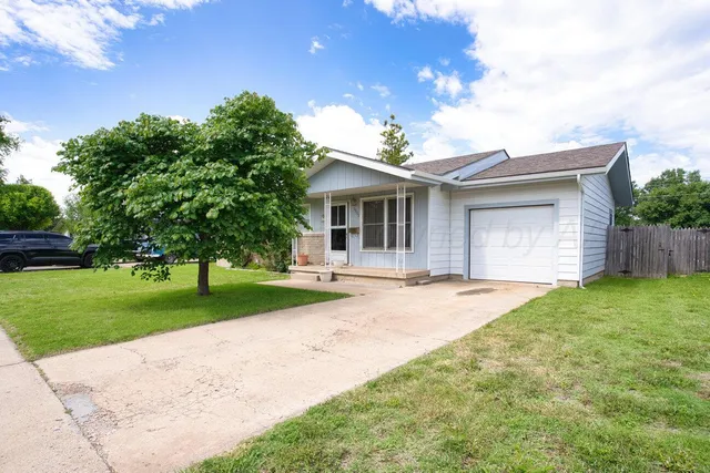 a front view of a house with a garden and trees