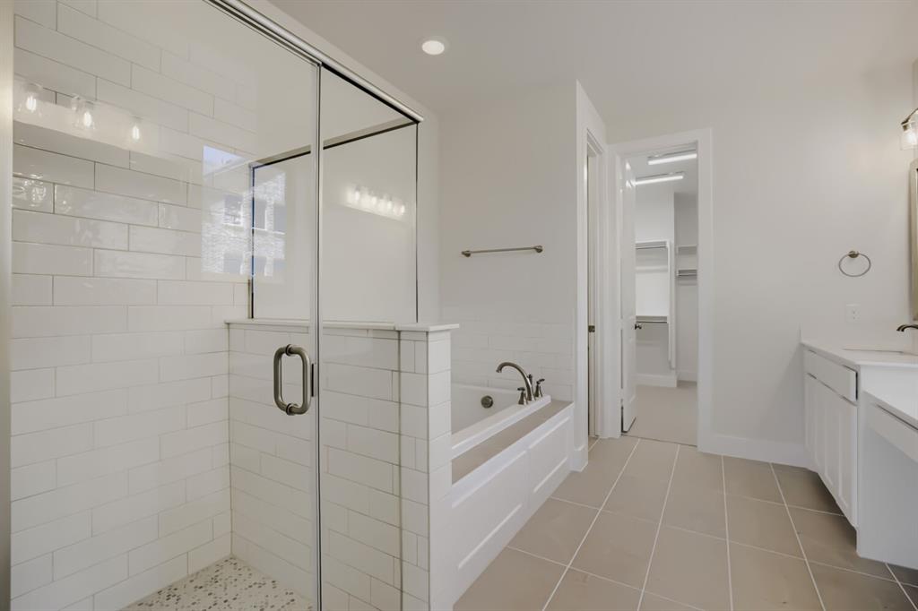 828 Stone Grv Road Lavon, TX 75166 - Photo 20 of 27 Spacious bathroom featuring a glass-enclosed shower with white subway tile, a built-in soaking tub, and neutral-toned floor tiling