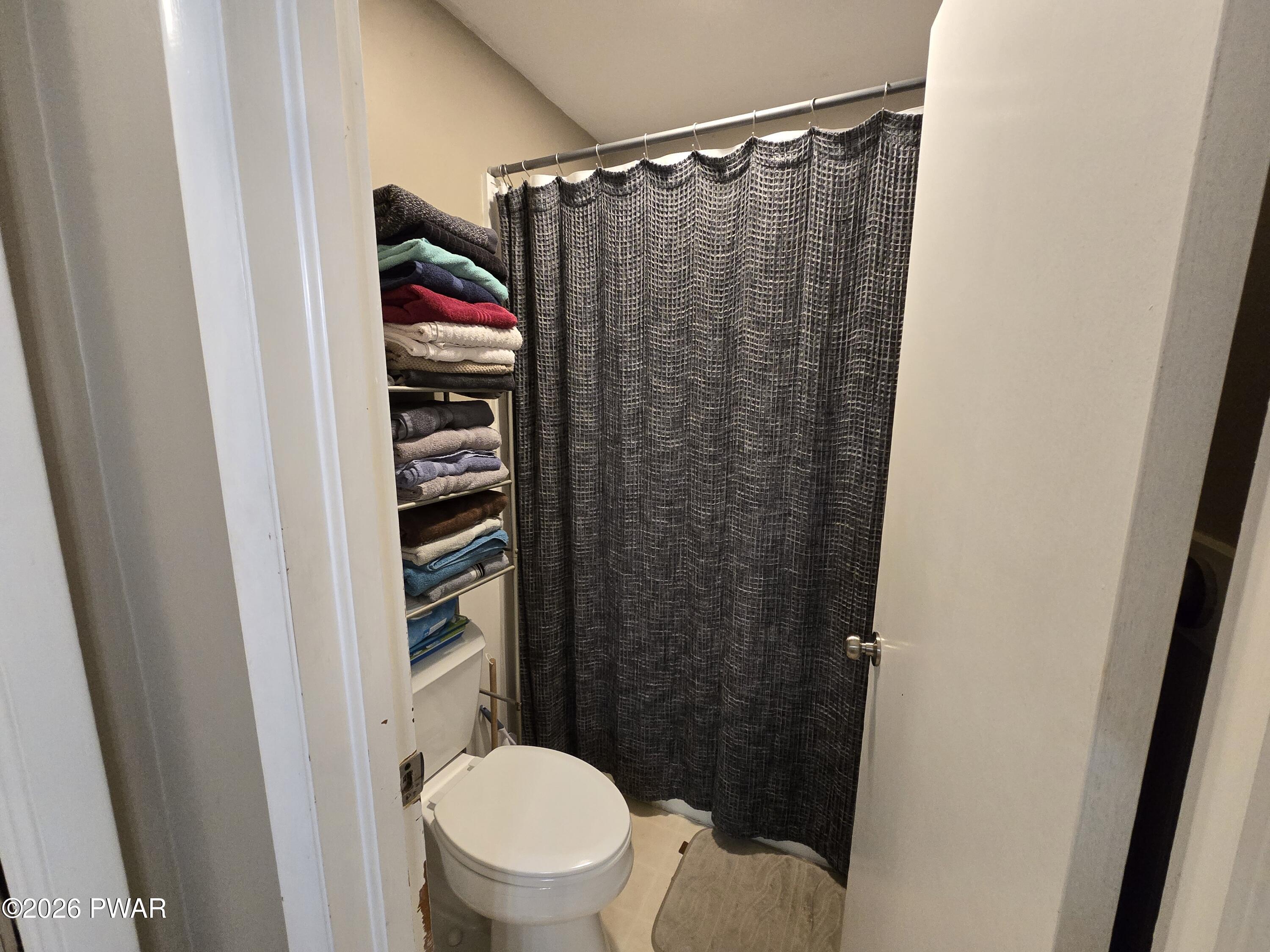 107 Keystone Hls Road, Unit 404 Factoryville, PA 18419 - Photo 4 of 23 a bathroom with a shower curtain and a toilet