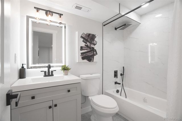 a bathroom with a bathtub shower sink vanity mirror and toilet