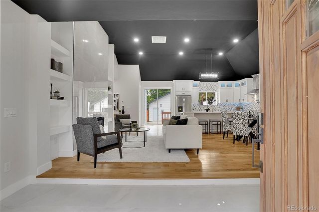 a living room with fireplace furniture and a view of kitchen