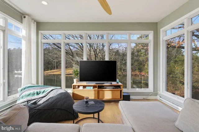 a living room with furniture a flat screen tv and a floor to ceiling window