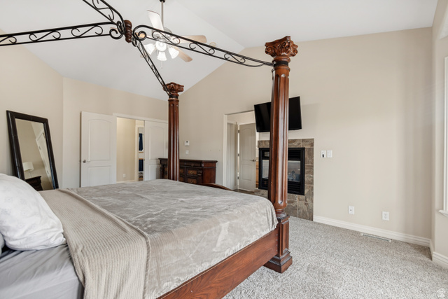 7296 Ridge Road Lake Point, UT 84074 - Photo 21 of 54 Vaulted ceiling bedroom featuring a fireplace with stone surround, wall-mounted television, and light gray carpet