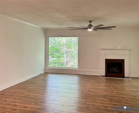 a view of empty room with wooden floor fireplace and fan