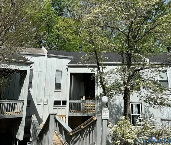 a view of house with patio outdoor seating and covered with trees