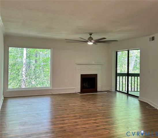 a view of empty room with wooden floor and fan