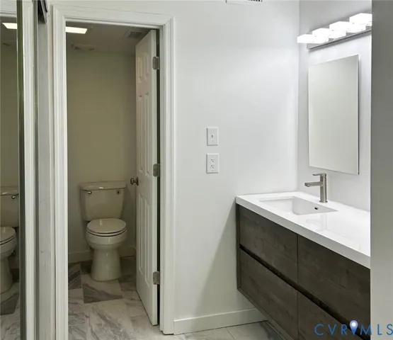 a bathroom with a granite countertop sink toilet and mirror