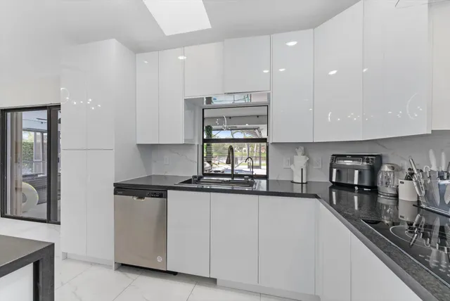 a kitchen with granite countertop white cabinets and stainless steel appliances