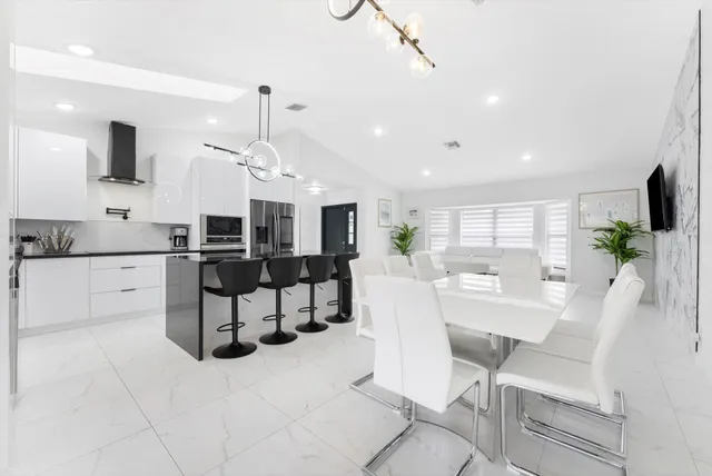 a large white kitchen with stainless steel appliances kitchen island granite countertop a sink and cabinets