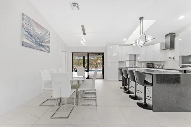 a kitchen with stainless steel appliances kitchen island granite countertop a table chairs sink and cabinets