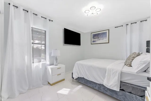 a bedroom with a bed and a flat tv screen on the dresser