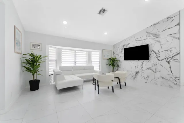 a living room with furniture a flat screen tv and a window