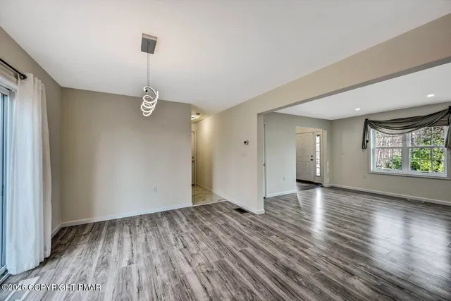 a view of empty room with wooden floor and window