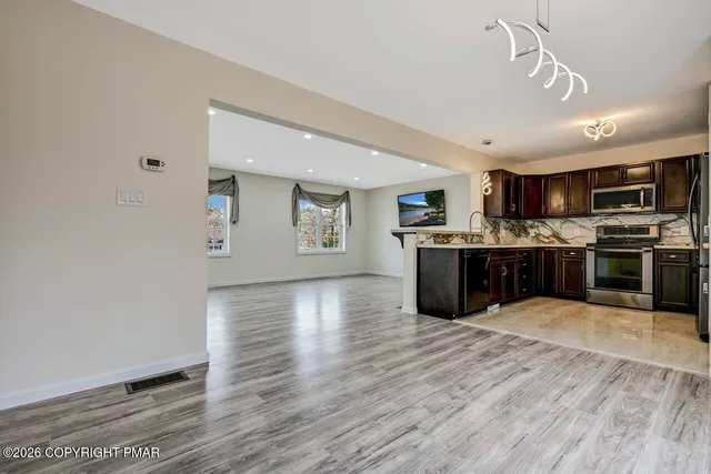 a large kitchen with stainless steel appliances granite countertop a stove top oven a sink dishwasher and a oven with wooden floor