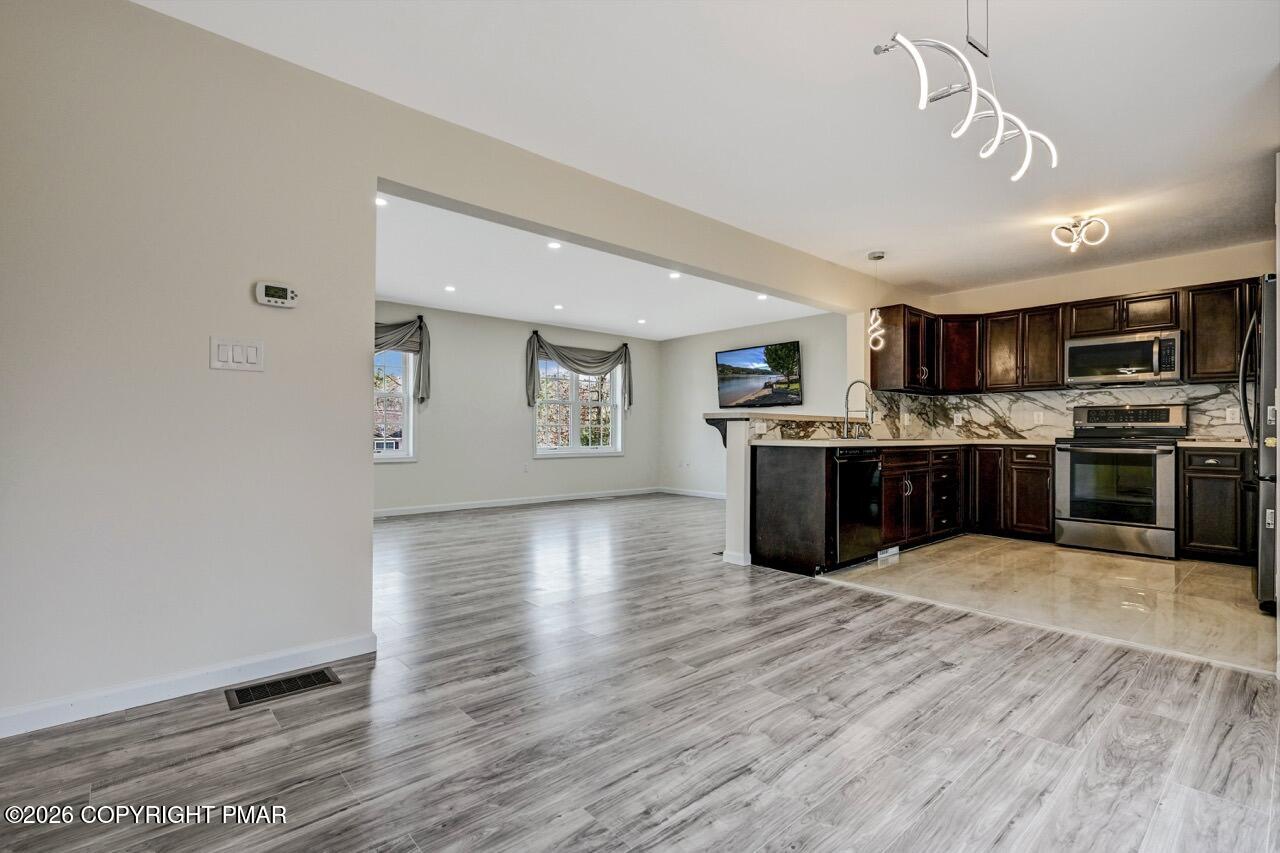1013 Bear Swamp Road East Stroudsburg, PA 18302 - Photo 13 of 53 a large kitchen with stainless steel appliances granite countertop a stove top oven a sink dishwasher and a oven with wooden floor