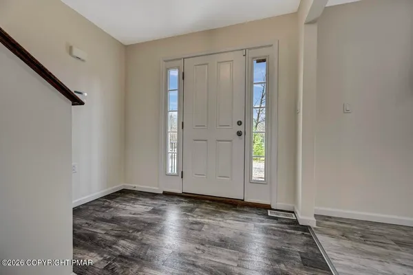 an empty room with wooden floor and windows