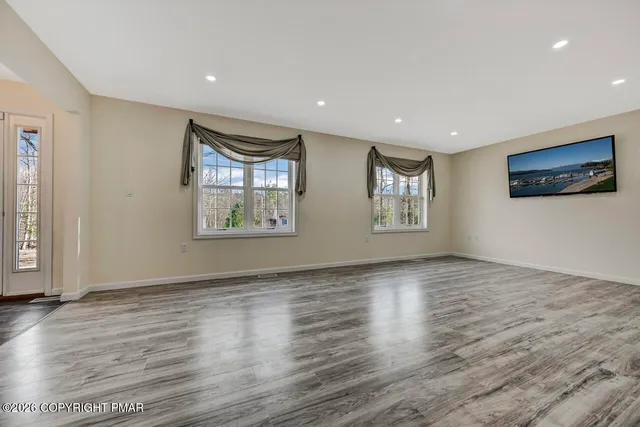 a view of an empty room with window and wooden floor
