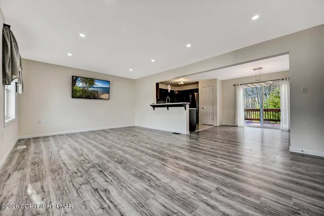 a view of kitchen with stainless steel appliances wooden floor and window
