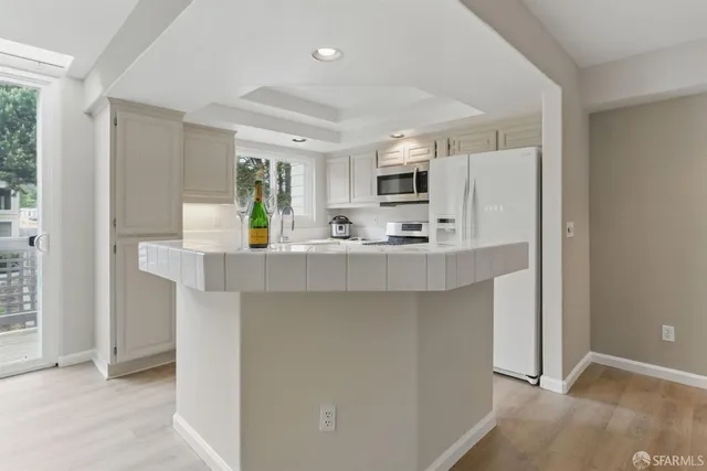 a kitchen with kitchen island white cabinets and refrigerator