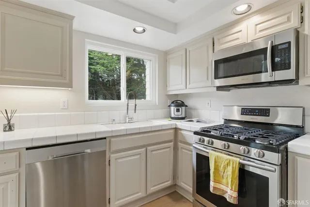 a kitchen with stainless steel appliances granite countertop white cabinets a sink and a stove