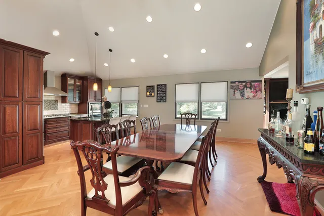 a dining room with stainless steel appliances kitchen island granite countertop a dining table chairs and a refrigerator