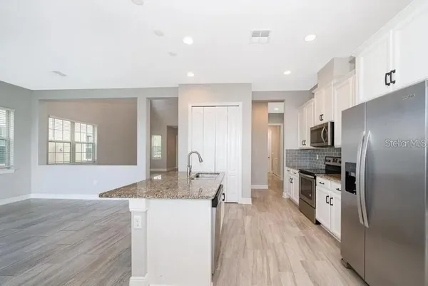 a kitchen with granite countertop a refrigerator stove top oven and sink