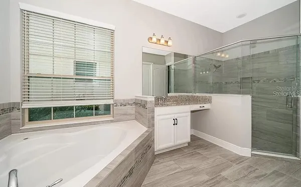 a bathroom with a granite countertop sink mirror and a bathtub