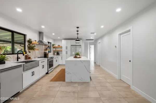 a large kitchen with kitchen island a large counter top a sink stainless steel appliances and cabinets