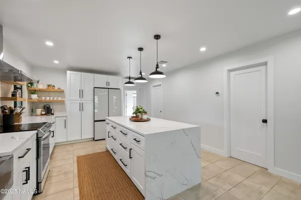 a kitchen with stainless steel appliances a stove a sink a refrigerator and white cabinets with wooden floor