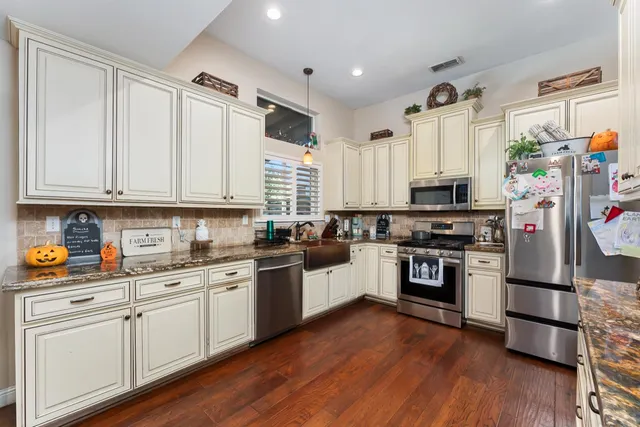 a kitchen with stainless steel appliances a stove a sink and white cabinets