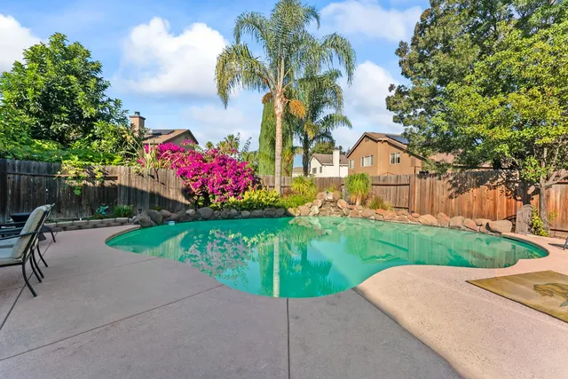 a patio with a table and chairs and potted plants
