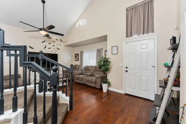 a view of a livingroom with furniture stairs wooden floor and a chandelier
