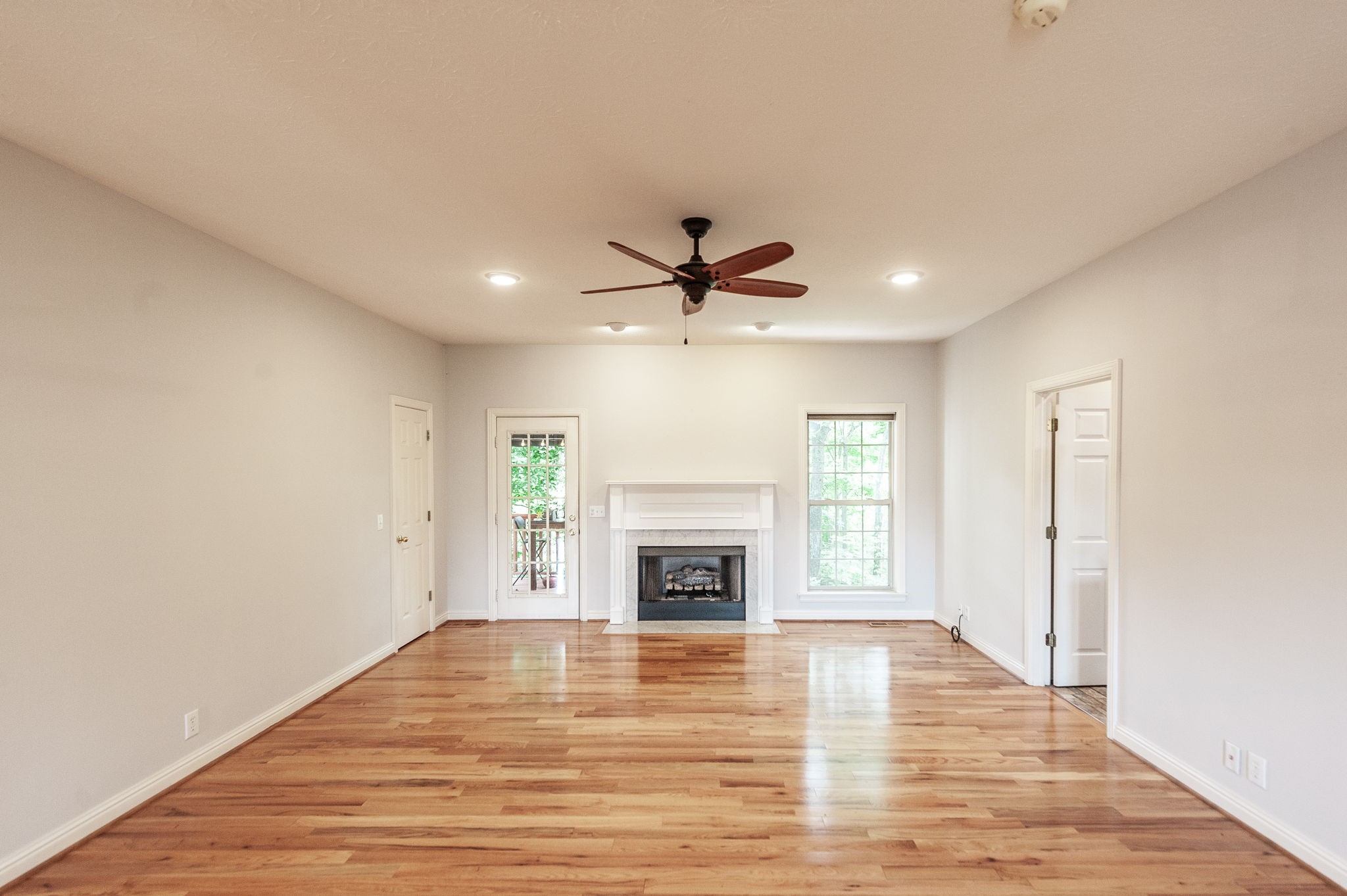 6513 North Mt Pleasant Road Greenbrier, TN 37073 - Photo 25 of 54 an empty room with fireplace wooden floor chandelier fan and windows